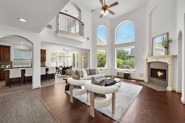 4603 Red Hawk Ct, Sugar Land, TX 77479 - living area featuring dark wood-style flooring, a tiled fireplace, ceiling fan, healthy amount of natural light, and a high ceiling