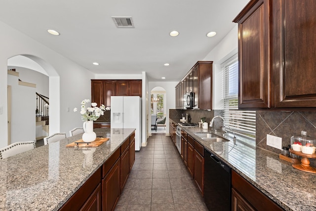 4603 Red Hawk Ct, Sugar Land, TX 77479 - kitchen featuring a sink, arched walkways, stainless steel appliances, backsplash, and light stone counters