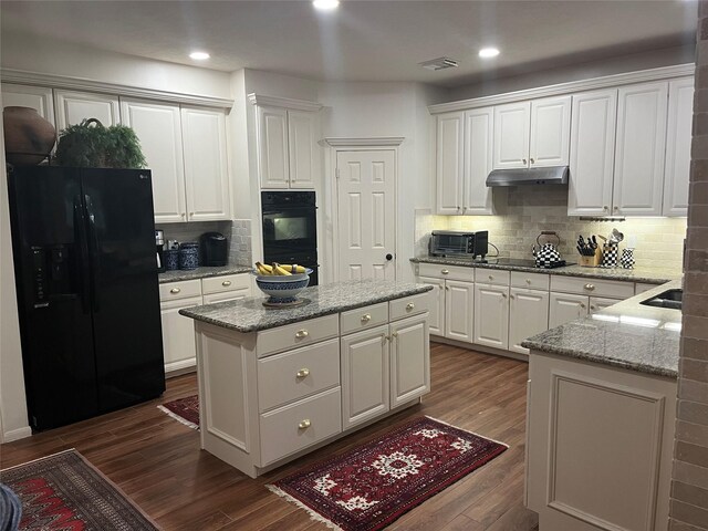 2103 Crescent Coral Dr, League City, TX 77573 - kitchen featuring black appliances, under cabinet range hood, a center island, white cabinets, and dark wood-style floors
