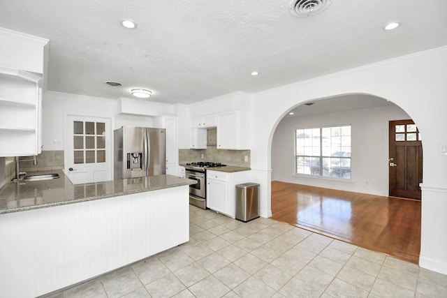 2606 Droxford Dr, Houston, TX 77008 - kitchen with appliances with stainless steel finishes, arched walkways, a sink, open shelves, and light tile patterned floors