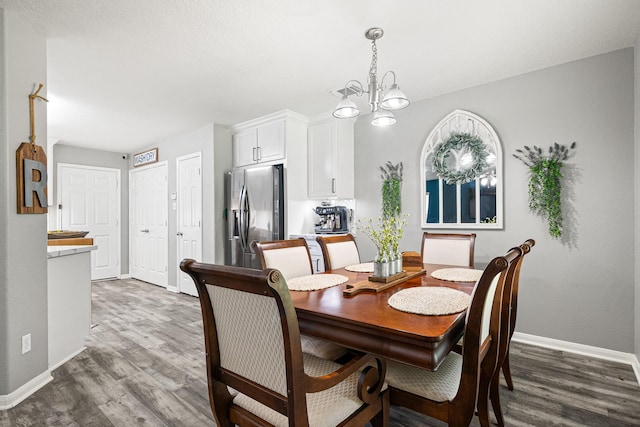 dining area featuring wood finished floors, baseboards, and a chandelier