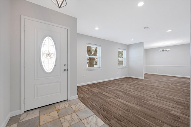 foyer entrance featuring a chandelier, baseboards, light wood-style floors, and recessed lighting
