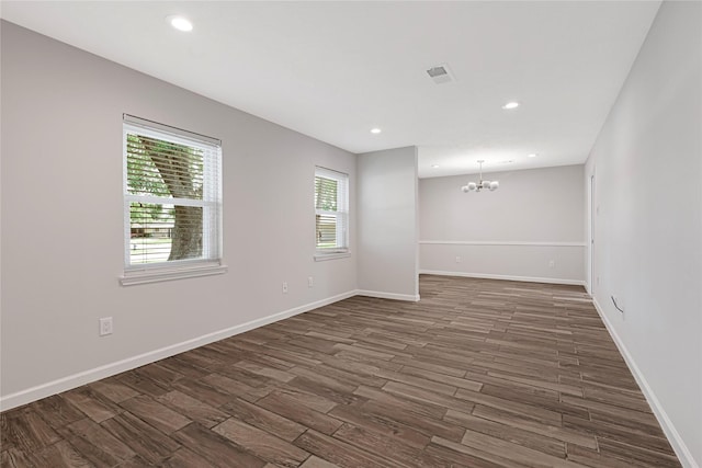 spare room featuring a chandelier, dark wood-style flooring, baseboards, and recessed lighting