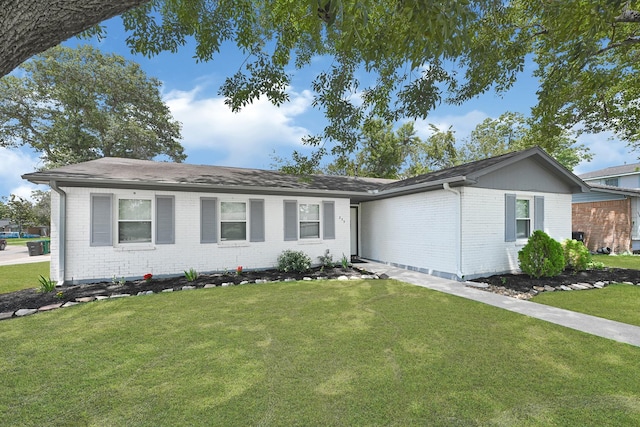 ranch-style home featuring brick siding, a front yard, and roof with shingles