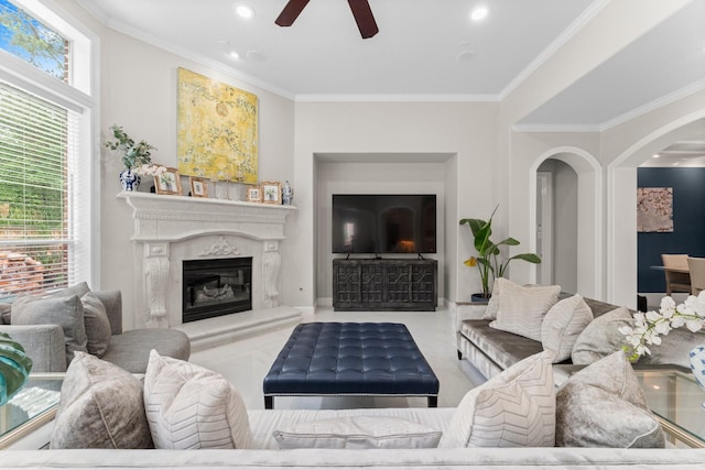 living area with arched walkways, a ceiling fan, recessed lighting, crown molding, and a fireplace