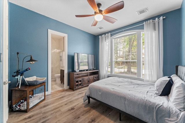 bedroom with wood finished floors, ensuite bath, ceiling fan, and a textured wall