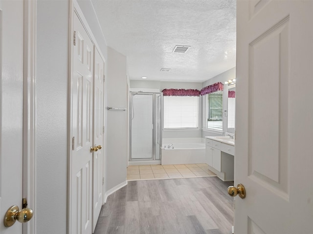 6123 Dove Fern Ct, Houston, TX 77041 - bathroom featuring a textured ceiling, a shower stall, a garden tub, wood finished floors, and vanity