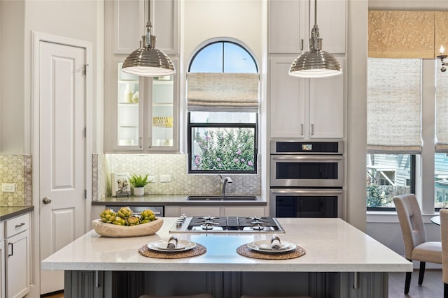 4404 Dickson St Unit B, Houston, TX 77007 - kitchen featuring appliances with stainless steel finishes, a sink, white cabinets, tasteful backsplash, and hanging light fixtures
