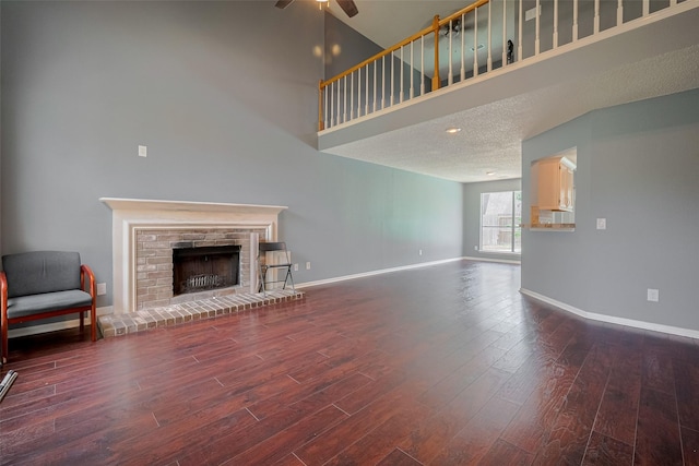 9911 Villa Verde Dr, Houston, TX 77064 - unfurnished living room with wood finished floors, a ceiling fan, baseboards, a brick fireplace, and a towering ceiling