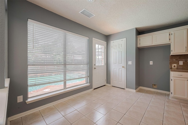 9911 Villa Verde Dr, Houston, TX 77064 - kitchen with a textured ceiling, plenty of natural light, light tile patterned floors, and white cabinetry