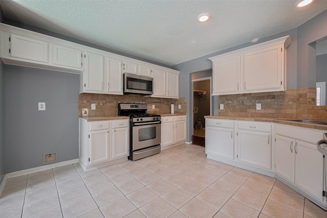 9911 Villa Verde Dr, Houston, TX 77064 - kitchen with stainless steel appliances, white cabinetry, backsplash, light tile patterned floors, and a textured ceiling