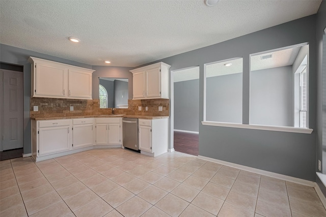 9911 Villa Verde Dr, Houston, TX 77064 - kitchen with stainless steel dishwasher, decorative backsplash, white cabinets, light tile patterned floors, and a textured ceiling