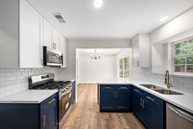 52 S High Oaks Cir, The Woodlands, TX 77380 - kitchen featuring appliances with stainless steel finishes, blue cabinets, a sink, white cabinetry, and recessed lighting
