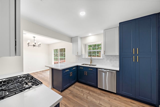 52 S High Oaks Cir, The Woodlands, TX 77380 - kitchen with stainless steel dishwasher, a sink, blue cabinetry, a peninsula, and light wood-style flooring
