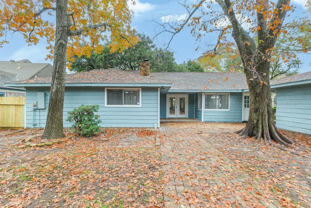 ranch-style house with french doors, a chimney, and fence