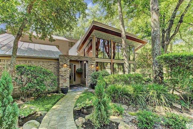 view of front of house with brick siding, a standing seam roof, and metal roof