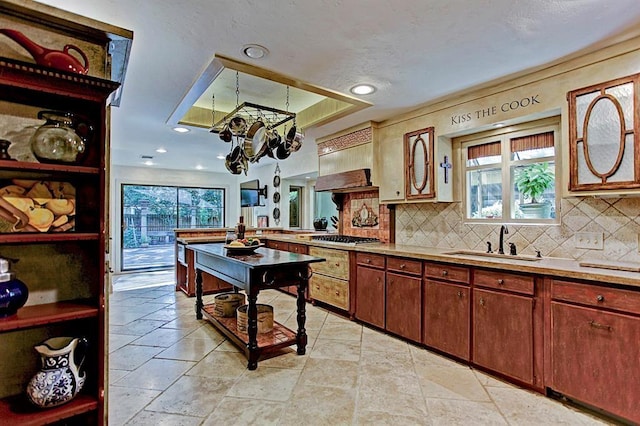 kitchen with a sink, tasteful backsplash, light countertops, a tray ceiling, and recessed lighting