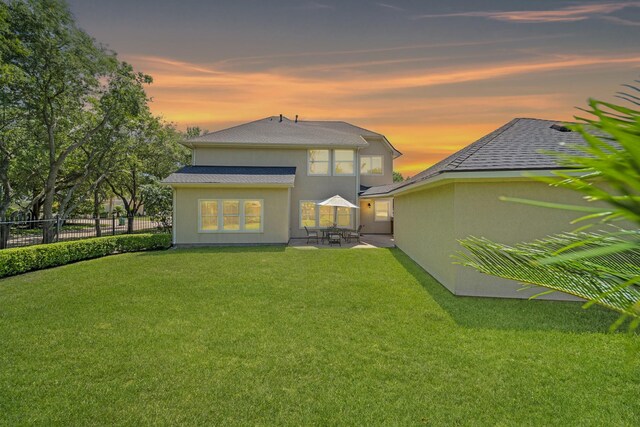 20002 Meadow Arbor Ct, Katy, TX 77450 - back of house at dusk featuring a patio area, stucco siding, and roof with shingles