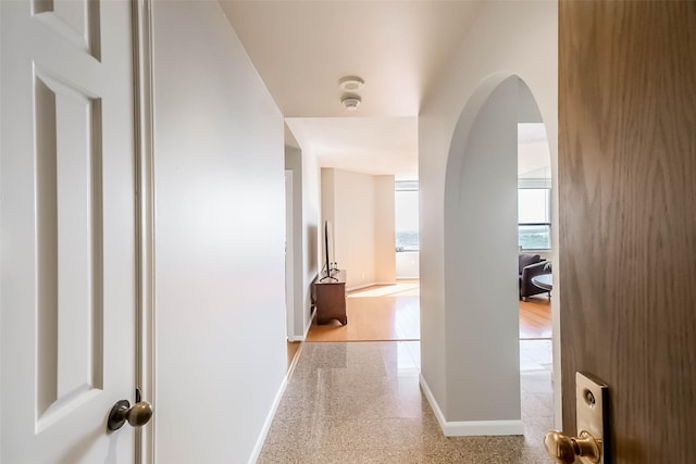 hall featuring baseboards and arched walkways