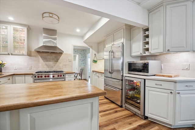 2618 Sunset Blvd, West University Place, TX 77005 - kitchen featuring wall chimney range hood, premium appliances, wine cooler, backsplash, and light wood-style floors