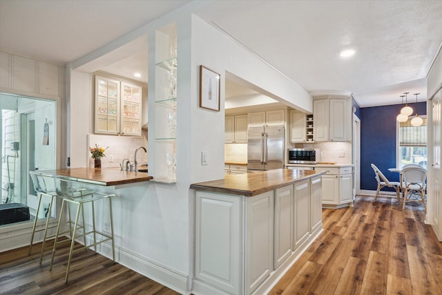 2618 Sunset Blvd, West University Place, TX 77005 - kitchen with appliances with stainless steel finishes, butcher block countertops, wood finished floors, decorative backsplash, and a peninsula