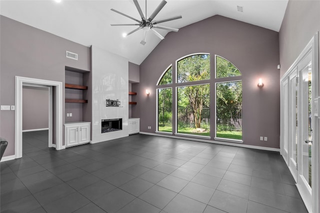 14834 Plantation Oak Dr, Houston, TX 77068 - unfurnished living room featuring ceiling fan, built in features, dark tile patterned floors, high vaulted ceiling, and a glass covered fireplace