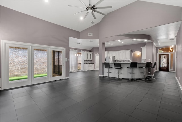 14834 Plantation Oak Dr, Houston, TX 77068 - living area featuring a ceiling fan, baseboards, arched walkways, dark tile patterned flooring, and high vaulted ceiling