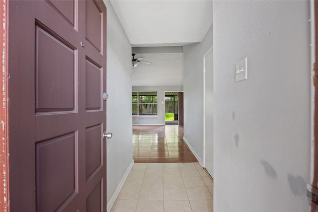 hall featuring baseboards and light tile patterned flooring