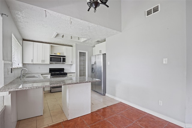 kitchen with appliances with stainless steel finishes, a sink, light stone counters, white cabinets, and a textured ceiling