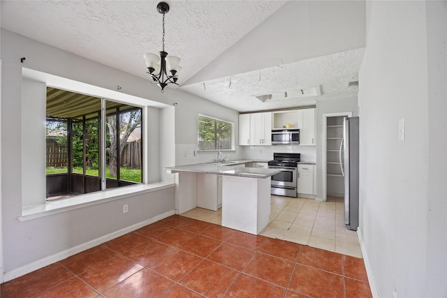 kitchen featuring appliances with stainless steel finishes, a textured ceiling, a peninsula, light tile patterned flooring, and white cabinets