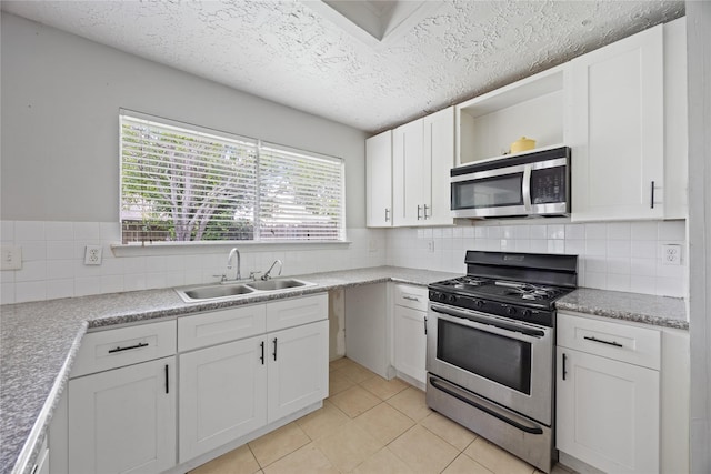 kitchen with stainless steel appliances, a sink, open shelves, white cabinetry, and a textured ceiling