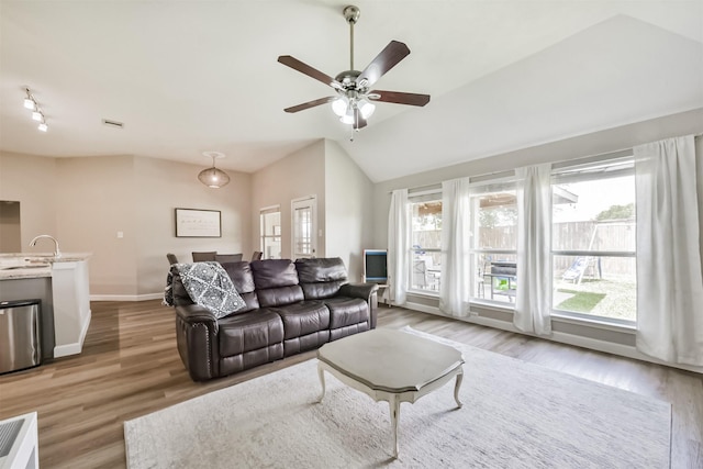 20810 Oak Rain Ct, Katy, TX 77449 - living area featuring healthy amount of natural light, lofted ceiling, light wood finished floors, a ceiling fan, and baseboards