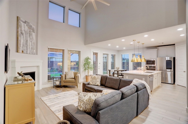 2327 Partridgeberry Ln, Katy, TX 77494 - living room with a fireplace, light wood finished floors, ceiling fan, a high ceiling, and recessed lighting