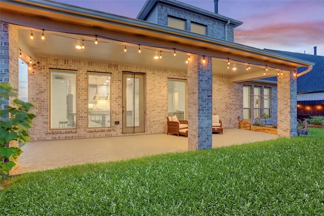 2327 Partridgeberry Ln, Katy, TX 77494 - back of property at dusk with a patio area, brick siding, and a yard