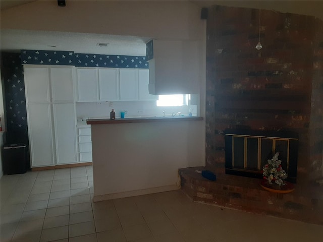 4927 Algernon Dr, Spring, TX 77373 - kitchen with white cabinetry, light tile patterned floors, and a fireplace
