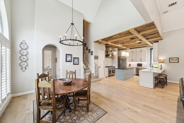 4323 Colony W Dr, Richmond, TX 77406 - dining room featuring arched walkways, light wood finished floors, stairs, a high ceiling, and a chandelier
