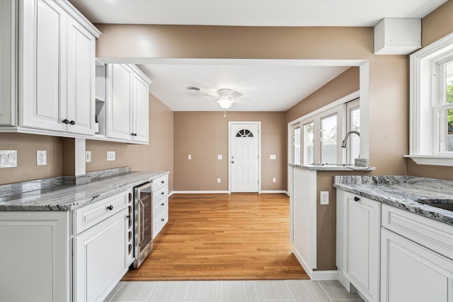 1803 Latexo Dr, Houston, TX 77018 - kitchen with white cabinetry, baseboards, light wood finished floors, ceiling fan, and beverage cooler