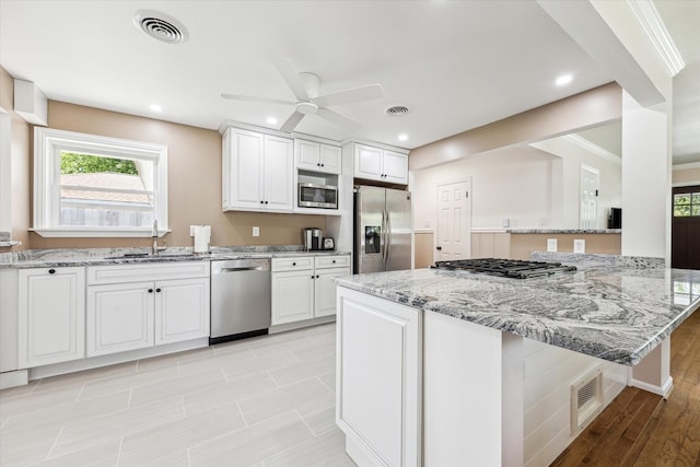 1803 Latexo Dr, Houston, TX 77018 - kitchen featuring stainless steel appliances, a sink, a ceiling fan, light stone counters, and healthy amount of natural light