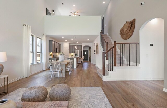 25701 Damask Dr, Magnolia, TX 77355 - dining area featuring arched walkways, a ceiling fan, light wood finished floors, a high ceiling, and stairway
