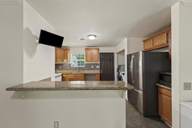1314 Robert St, Baytown, TX 77521 - kitchen featuring stainless steel appliances, a sink, a peninsula, independent washer and dryer, and tasteful backsplash