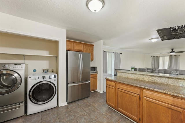 1314 Robert St, Baytown, TX 77521 - kitchen featuring stainless steel appliances, brown cabinets, washer and clothes dryer, a ceiling fan, and light stone countertops