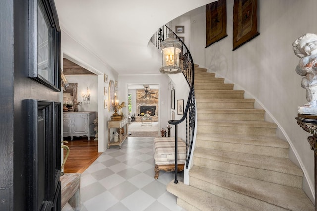 5610 Edgewick Ct, Houston, TX 77069 - foyer entrance featuring a lit fireplace, tile patterned floors, stairs, and crown molding