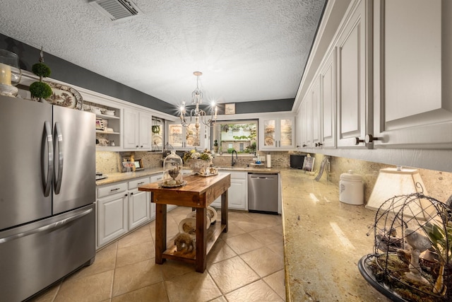 5610 Edgewick Ct, Houston, TX 77069 - kitchen featuring stainless steel appliances, a chandelier, tasteful backsplash, white cabinetry, and light stone counters