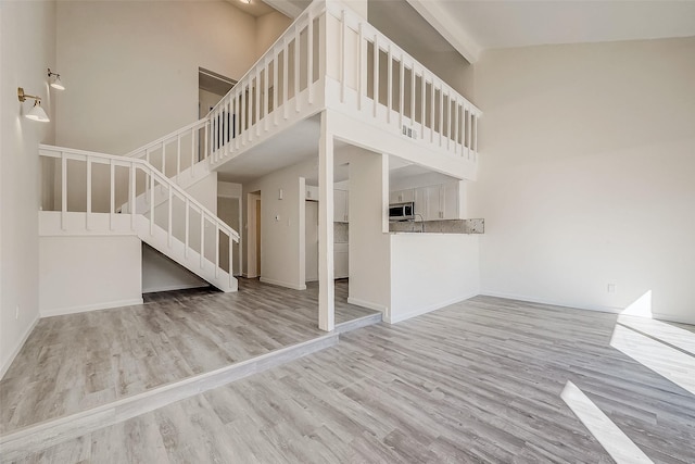 12632 Newbrook Dr, Houston, TX 77072 - unfurnished living room featuring high vaulted ceiling, stairway, wood finished floors, and baseboards