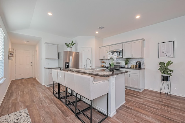 5418 Wyndham Ridge Ln, Spring, TX 77373 - kitchen featuring stainless steel appliances, a breakfast bar, an island with sink, light wood-type flooring, and backsplash