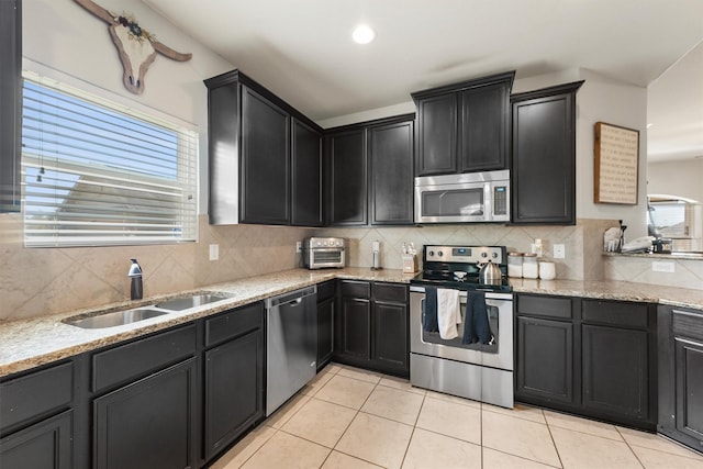 22607 August Crow Dr, Hockley, TX 77447 - kitchen featuring stainless steel appliances, a sink, light tile patterned floors, tasteful backsplash, and light stone countertops