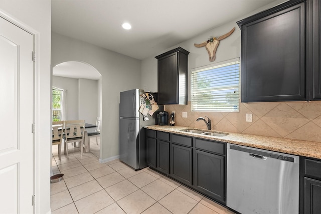 22607 August Crow Dr, Hockley, TX 77447 - kitchen featuring appliances with stainless steel finishes, a sink, arched walkways, tasteful backsplash, and recessed lighting