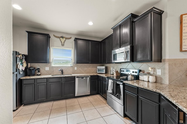 22607 August Crow Dr, Hockley, TX 77447 - kitchen with appliances with stainless steel finishes, a sink, tasteful backsplash, and light tile patterned flooring