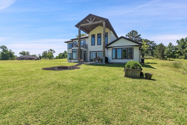 145 Grandview Blvd, Montgomery, TX 77356 - rear view of house featuring a balcony, a yard, stucco siding, and a fire pit