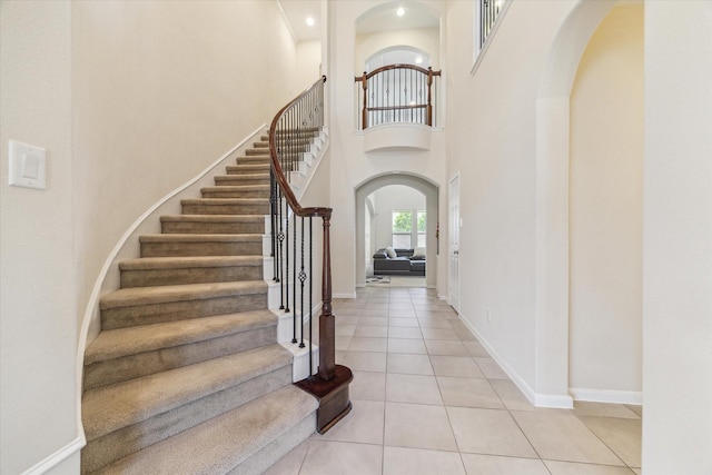 6015 Turner Shadow Ln, Sugar Land, TX 77479 - foyer featuring arched walkways, light tile patterned flooring, stairs, baseboards, and a high ceiling
